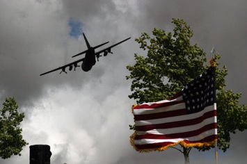 A C-130 Hercules flies over the American Flag at the Iron Mike memorial ceremony at La Fierre, France, June 7, 2009. Hundreds came to honor those who sacrificed so much 65 years ago in this very same field. (U.S. Army Photo by Ms. Lea Greene/Released)
